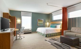 a modern hotel room with a large bed , couch , and desk , along with curtains and a rug at Home2 Suites by Hilton Downingtown Exton Route 30