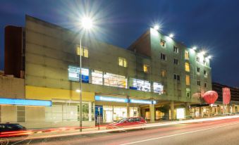 a city street at night , with a row of buildings on the corner and cars passing by at Stay Hotel Guimarães Centro