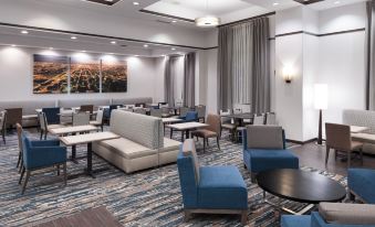 a large , modern hotel lobby with various seating arrangements , including couches and chairs , as well as tables and benches at Hampton Inn & Suites Chicago-North Shore/Skokie