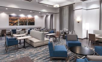 a large , modern hotel lobby with various seating arrangements , including couches and chairs , as well as tables and benches at Hampton Inn & Suites Chicago North Shore