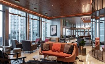 a large , modern living room with multiple couches and chairs arranged around a dining table at The Charter Hotel Seattle, Curio Collection by Hilton
