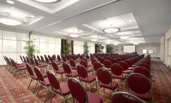 a large conference room with rows of red chairs arranged in a semicircle , ready for an event at Embassy Suites by Hilton Fort Myers Estero