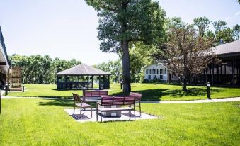 a park with a gazebo , benches , and trees in the background , under a clear blue sky at Okoboji Commons Hotel, Trademark Collection by Wyndham