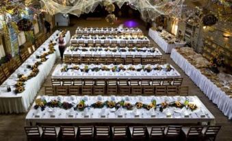 a long banquet table is set up with white tablecloths and flowers , surrounded by chairs at Hotel Boss