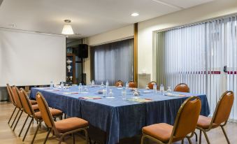 a conference room with a large table covered in a blue tablecloth , surrounded by several chairs at Hotel Palacios