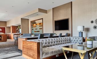 a modern living room with a wooden couch , a tv , and a coffee table in front of a bar at Cleveland Marriott East