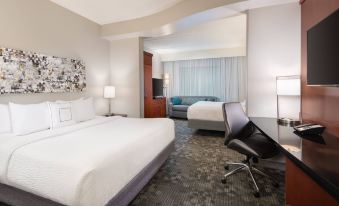 a modern hotel room with a large bed , white linens , and a black chair near the window at Courtyard Pittsburgh Washington/Meadow Lands