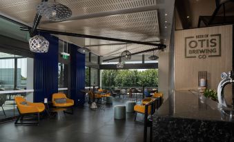 a modern restaurant with blue and yellow seating , dining tables , chairs , and a bar area at Rydges Campbelltown an EVT hotel