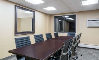 a conference room with a large wooden table surrounded by black chairs and a mirror on the wall at Ramada by Wyndham Minneapolis Golden Valley