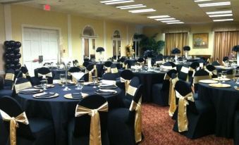 a large dining room with several round tables covered in black tablecloths , creating a formal atmosphere at White Columns Inn