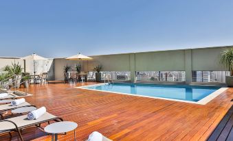 a rooftop pool surrounded by a wooden deck , with lounge chairs and umbrellas placed around the pool area at San Marino Suites Hotel by Nobile