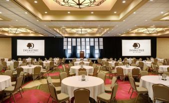 a large conference room with round tables and chairs , a stage at the end , and a dockertel logo on the wall at DoubleTree by Hilton Seattle Airport