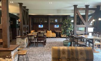 a modern restaurant with wooden tables , chairs , and couches , as well as a bar area with tvs at The Bridge Inn