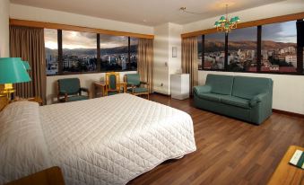 a spacious hotel room with a king - sized bed , a couch , and a window overlooking a cityscape at Hotel Diplomat