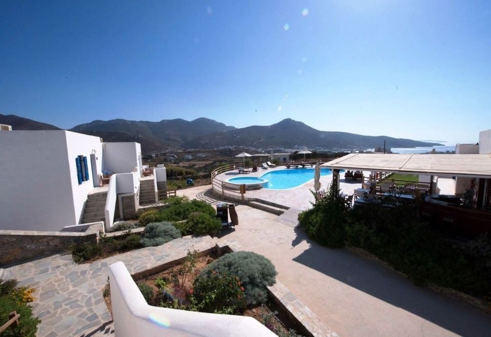 a luxurious resort with a large pool surrounded by white buildings and mountains in the background at Amorgion Hotel