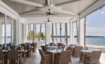 an outdoor dining area with a view of the ocean , featuring several tables and chairs arranged for guests at Isla Bella Beach Resort & Spa - Florida Keys