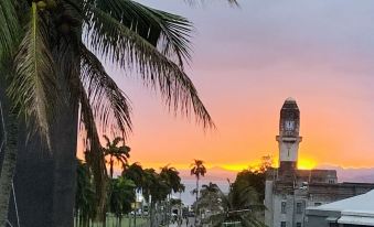 a beautiful sunset over a tropical city , with palm trees and a church in the background at Suva Motor Inn