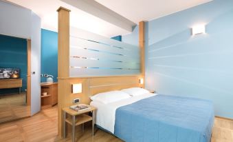 a modern bedroom with a wooden bed , blue walls , and a white comforter on the bed at Garda Hotel