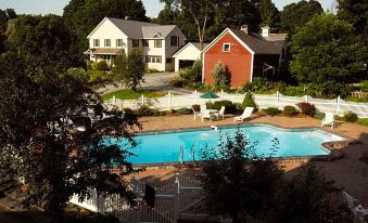 a large house with a red roof is surrounded by a white fence and has a swimming pool in front of it at The Brandon Inn