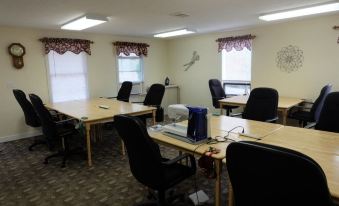 a conference room with multiple desks and chairs arranged in rows , along with a computer on one of the desks at Seams Like Home B&B