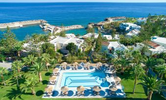 a beautiful resort with a large pool surrounded by lounge chairs and umbrellas , located near the ocean at Iberostar Selection Creta Marine