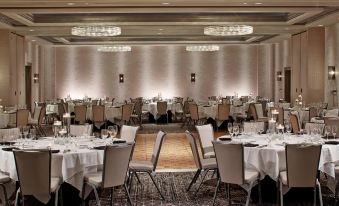 a large banquet hall filled with numerous tables and chairs , ready for a formal event at Rochester Airport Marriott