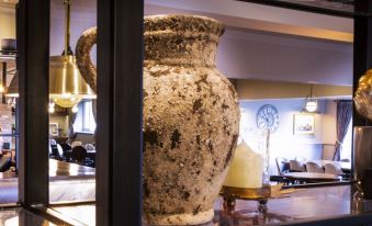 a large , ancient vase with a handle is displayed in a room with other decorative items at Stamford Gate Hotel