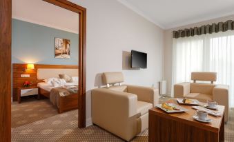 a hotel room with two beds , a couch , and a tv , all set against white walls at Best Western Hotel Jurata