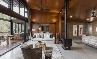 a modern living room with wooden ceiling and walls , a white couch , and a fireplace at Spicers Sangoma Retreat