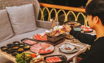 A woman stands while another person sits at a table with plates and food at La Lanna Resort