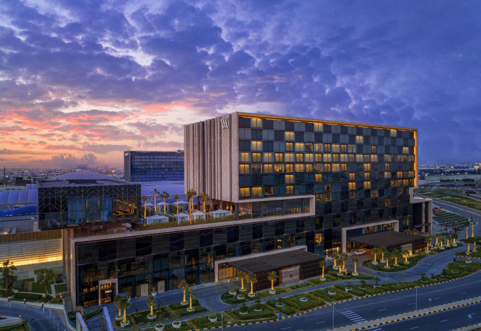 a modern , multi - level hotel building with a unique glass facade and a large central atrium , surrounded by lush greenery and a serene atmosphere at Waldorf Astoria Kuwait