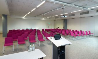 a conference room with a large table and chairs , and a projector screen on the wall at Mercure Geneva Airport