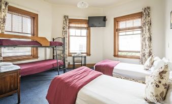 a room with three beds , one of which is a bunk bed , and a television mounted on the wall at The Cambridge Hotel