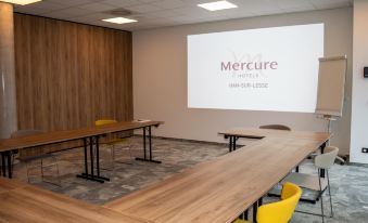 a large conference room with multiple wooden tables and chairs , a projector screen , and a projector screen on the wall at Mercure HAN Sur Lesse