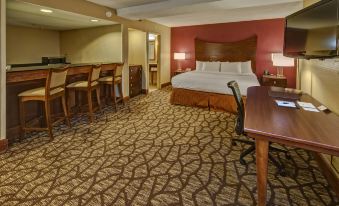 a hotel room with a king - sized bed , a dining table , chairs , and a television at DoubleTree by Hilton Hotel Oak Ridge-Knoxville