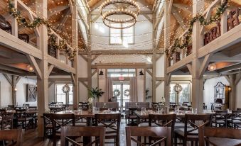 a large , open room with wooden floors and high ceilings is decorated with chandeliers and christmas decorations at Briar Barn Inn