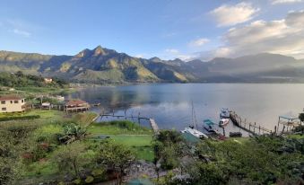 a beautiful mountainous landscape with a large lake , lush green trees , and boats docked on the shore at Eco Hotel Uxlabil Atitlan