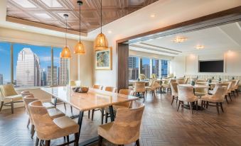 a modern restaurant with wooden tables and chairs , hanging lights , and a city view outside at Hyatt Regency Calgary