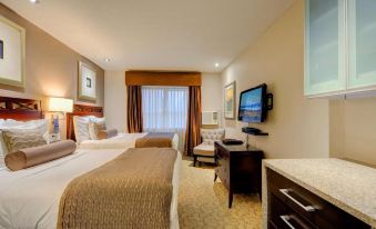 a hotel room with two beds , a tv , and a desk , all neatly arranged in a modern living space at Red Lion Inn and Suites Victoria