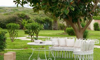 a white patio set is placed on a grassy lawn with trees in the background at Grecotel Meli Palace
