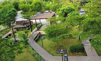 aerial view of a resort with a wooden walkway leading to the entrance , surrounded by lush greenery and trees at Baan Rai Darun Home Stay and Scenery Raft