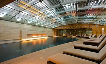 an indoor swimming pool surrounded by lounge chairs , with a fireplace in the background at Lucknam Park Hotel