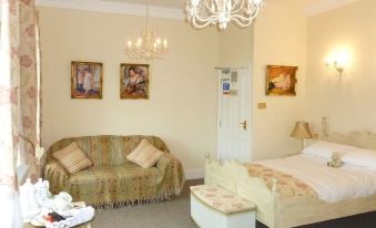 a large bedroom with a bed , couch , and chandelier is decorated in beige and white colors at The Brewers Arms