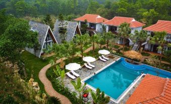 a luxurious resort with multiple buildings , a swimming pool , and lush greenery , set against the backdrop of a misty mountains at Bai Dinh Garden Resort & Spa