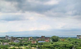 a cityscape with buildings , trees , and a cloudy sky is shown from an aerial perspective at Richmond Hotel Sylhet