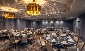 a large , well - lit banquet hall with multiple round tables and chairs set up for a formal event at Somerset Hills Hotel, Tapestry Collection by Hilton