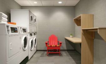a laundry room with a red chair placed in front of a washer and dryer at Home2 Suites by Hilton Easton