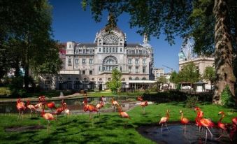 a large building with a dome is surrounded by pink flamingos in a park at Hampton by Hilton Antwerp Central Station