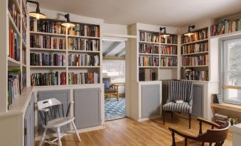 a room with bookshelves filled with books , a chair , and a dining table , creating a cozy reading area at The Deers Head Inn Tavern