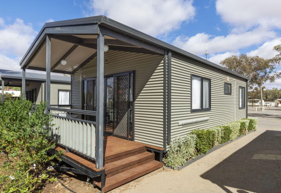 a small , modern house with a wooden deck and a metal roof , situated in a residential area at Broken Hill Tourist Park